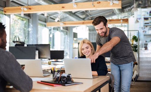 A colleague pointing to a laptop screen while others look on.