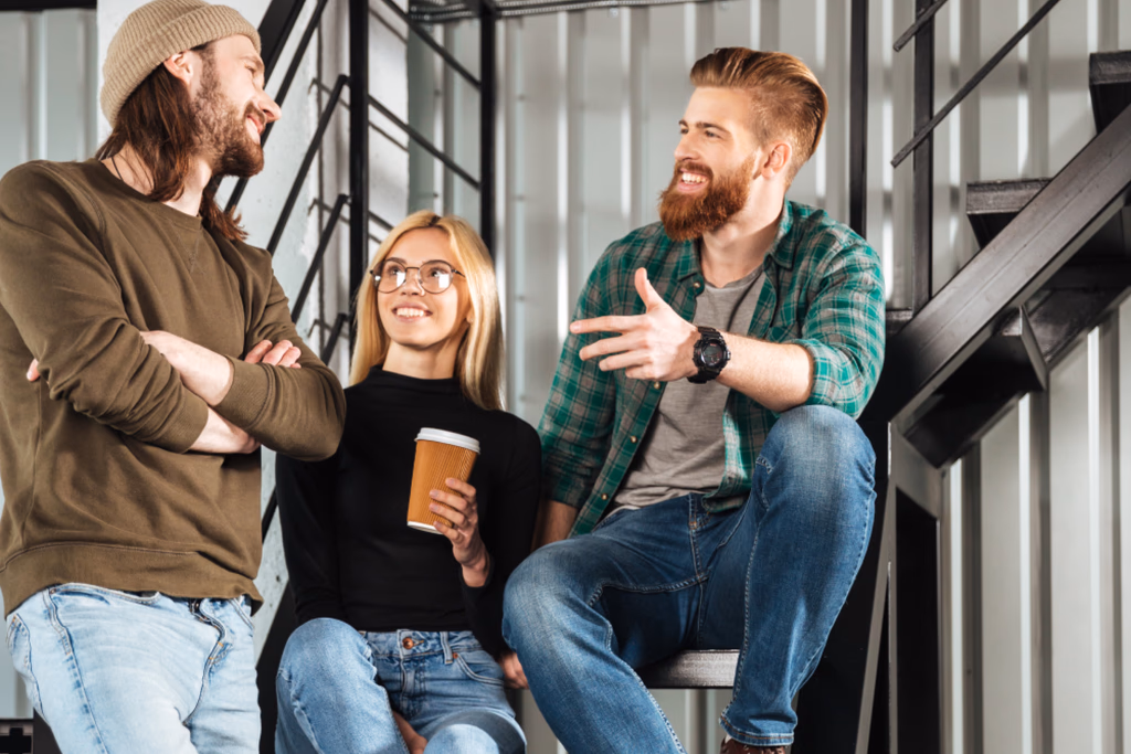Three people chatting on an indoor staircase with a takeaway coffee.